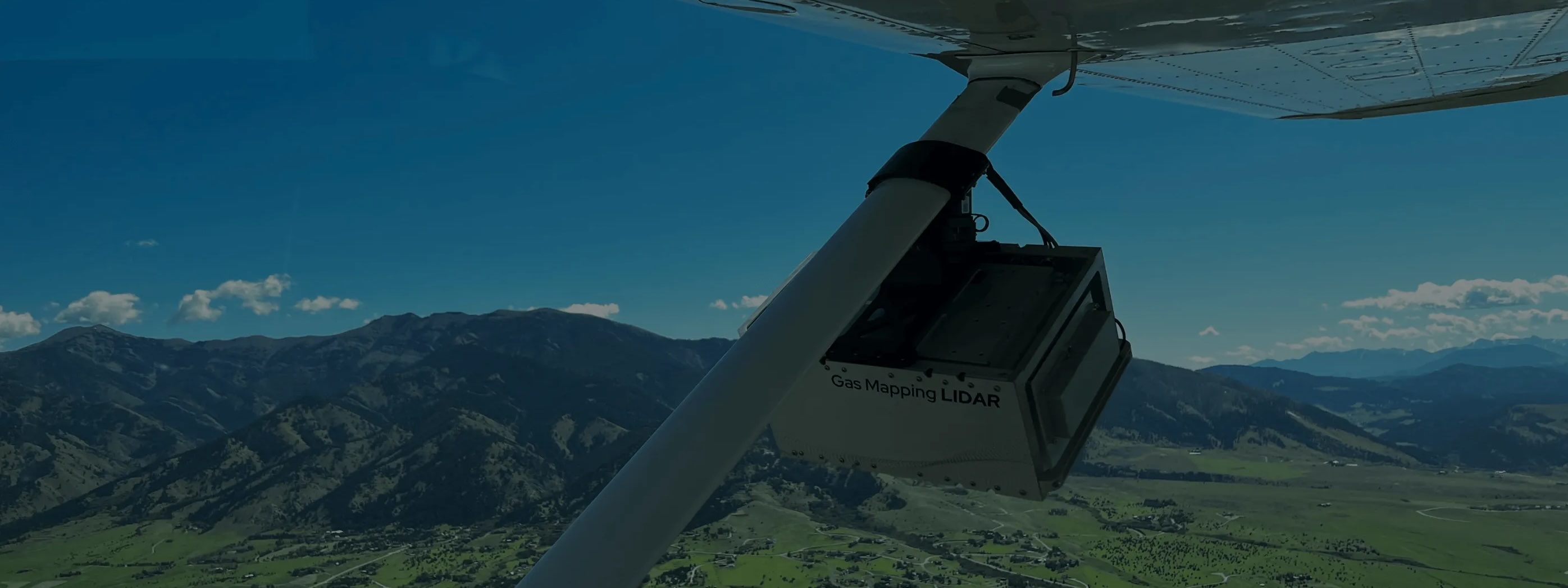 GML device attached to a plane flying over mountains against a clear blue sky